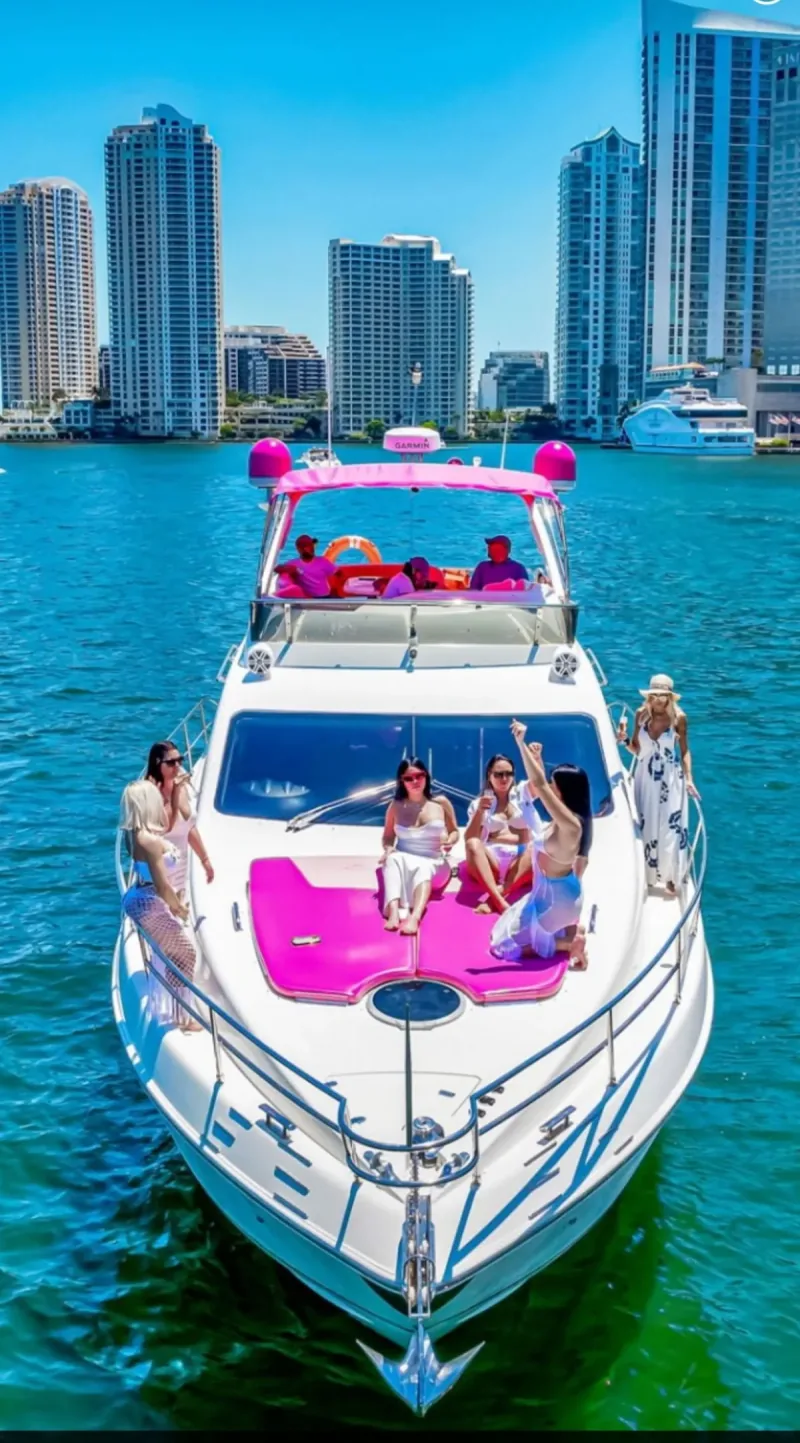 Captain Alain's pink yacht with guests aboard, Miami skyline behind